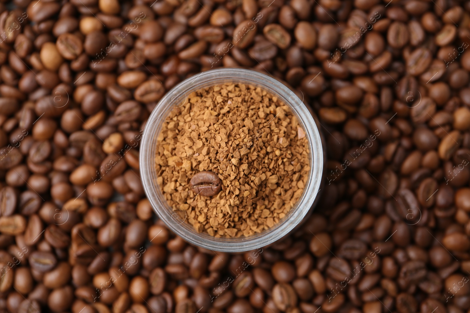 Glass jar with granulated instant coffee on beans, top view Photo of Glass jar with granulated instant coffee on beans, top view