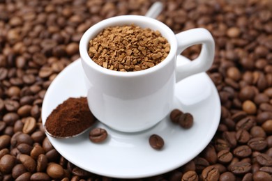 Photo of Cup with granulated instant coffee and powder on beans, closeup