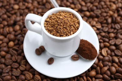 Photo of Cup with granulated instant coffee and powder on beans, closeup