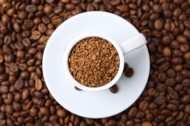 Photo of Cup with granulated instant coffee on beans, top view