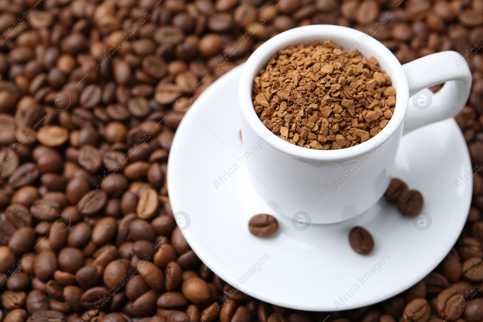 Cup with granulated instant coffee on beans, closeup. Space for text Photo of Cup with granulated instant coffee on beans, closeup. Space for text