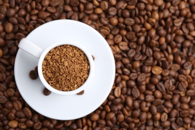 Photo of Cup with granulated instant coffee on beans, top view. Space for text