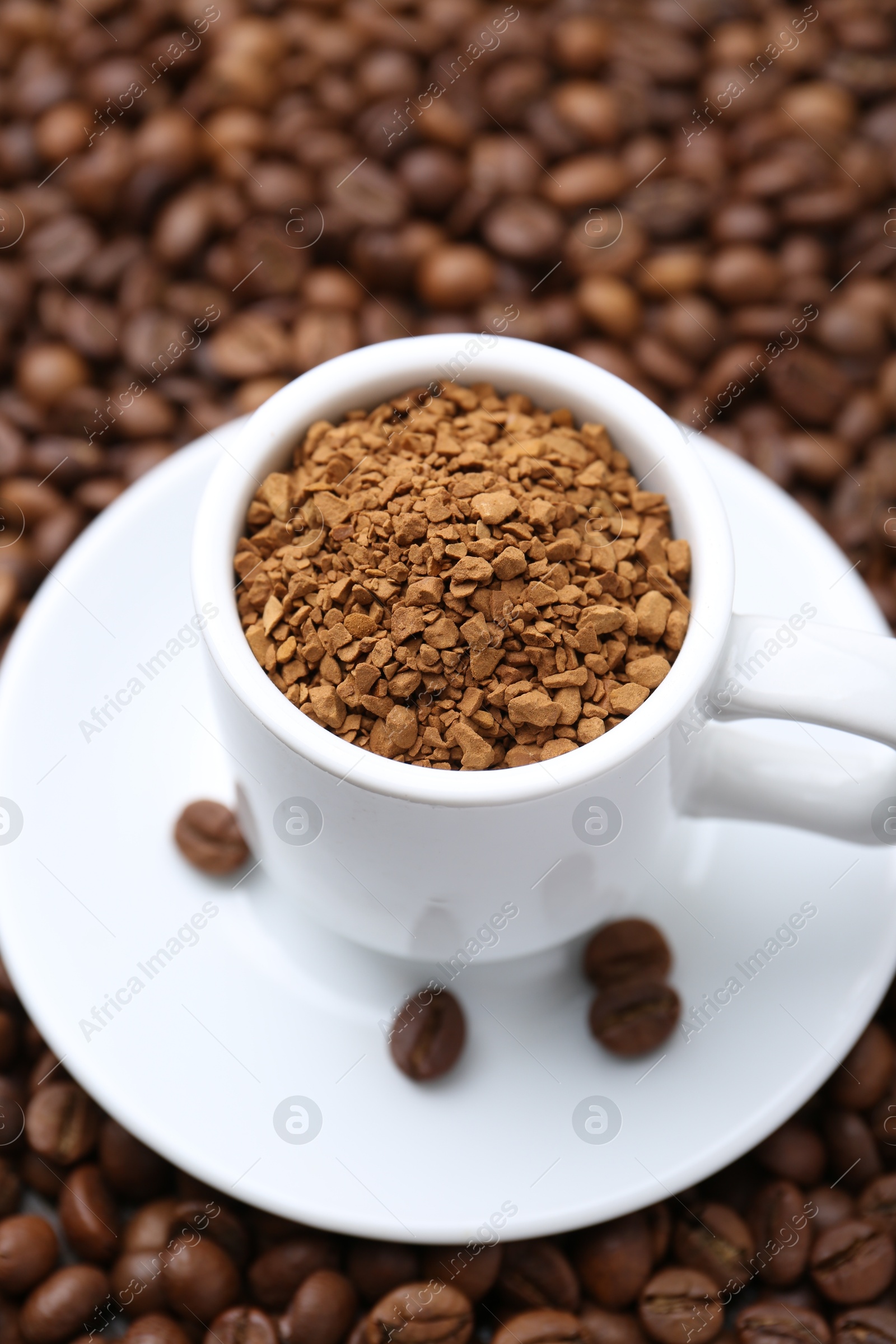 Cup with granulated instant coffee on beans, closeup Photo of Cup with granulated instant coffee on beans, closeup