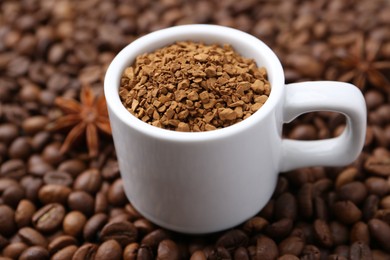 Photo of Cup with granulated instant coffee and star anise on beans, closeup
