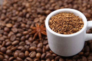 Photo of Cup with granulated instant coffee and star anise on beans, closeup. Space for text