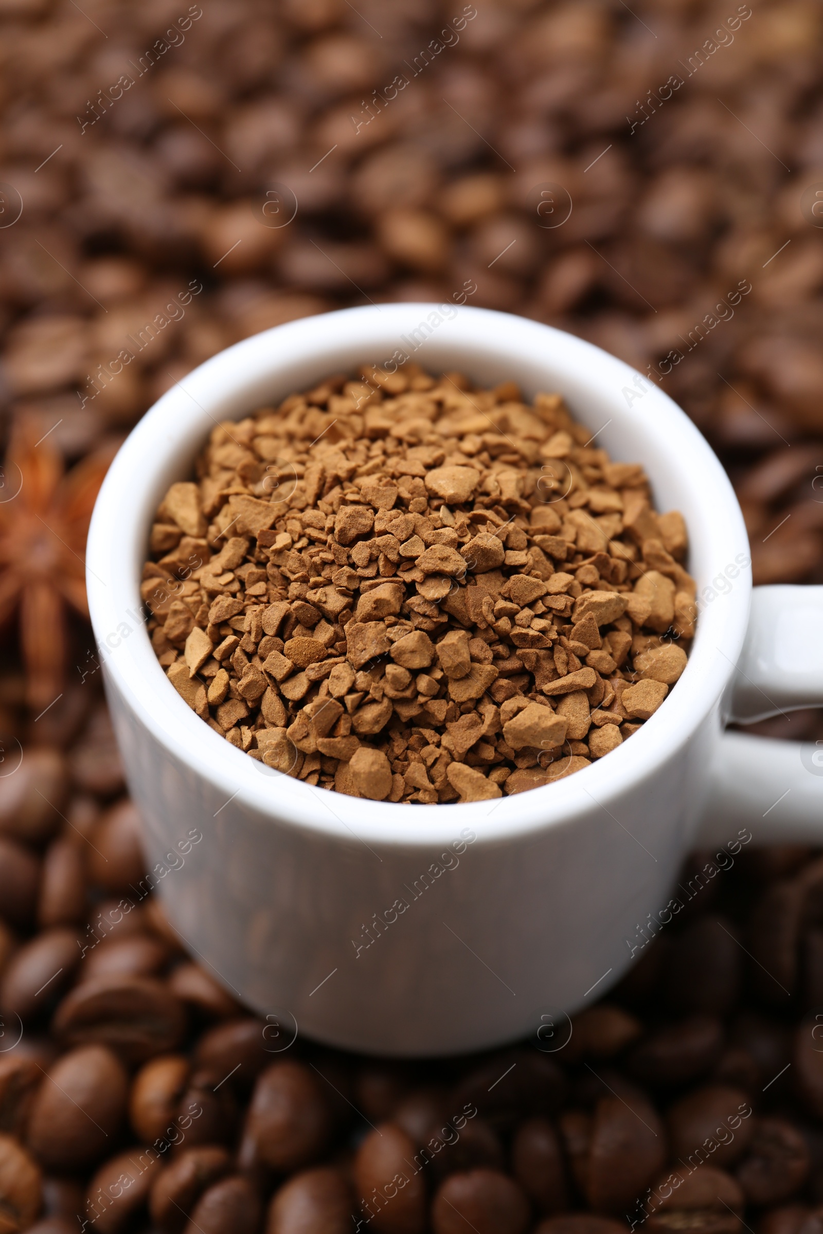 Cup with granulated instant coffee and star anise on beans, closeup Photo of Cup with granulated instant coffee and star anise on beans, closeup