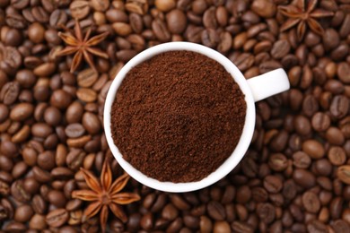 Photo of Cup with instant coffee powder and star anise on beans, top view