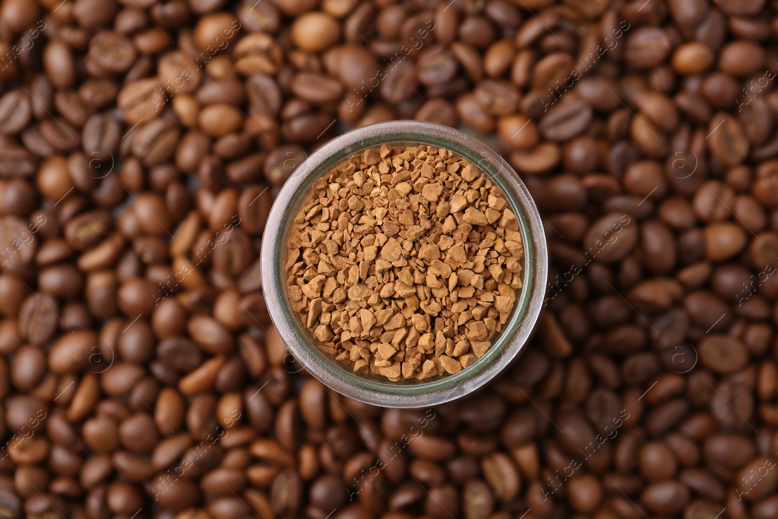 Glass jar with granulated instant coffee on beans, top view Photo of Glass jar with granulated instant coffee on beans, top view