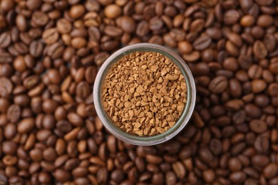 Photo of Glass jar with granulated instant coffee on beans, top view
