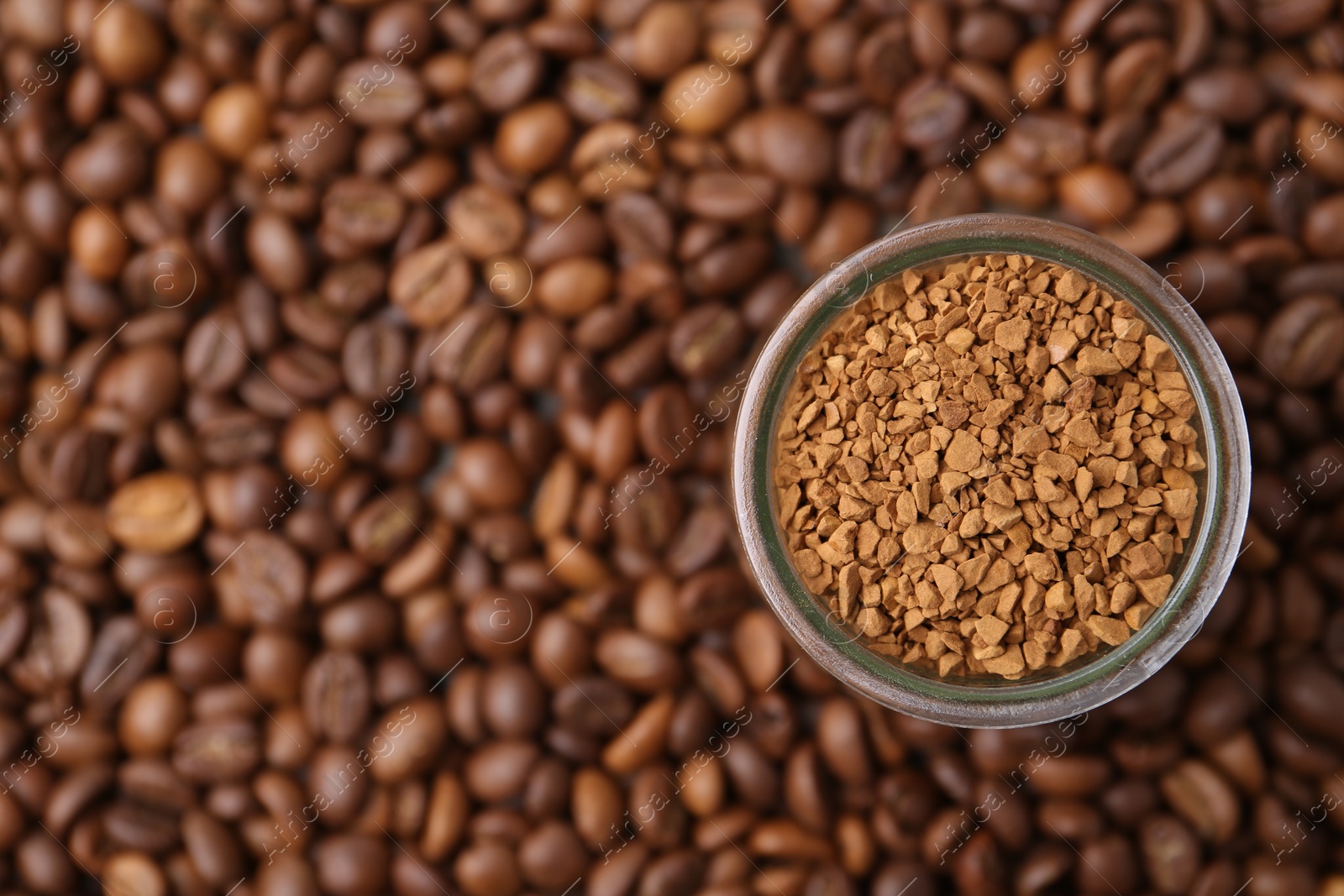Glass jar with granulated instant coffee on beans, top view. Space for text Photo of Glass jar with granulated instant coffee on beans, top view. Space for text