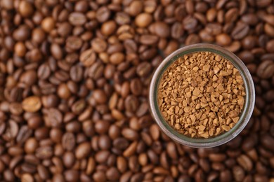 Photo of Glass jar with granulated instant coffee on beans, top view. Space for text