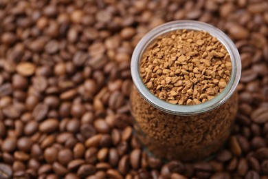 Photo of Glass jar with granulated instant coffee on beans, closeup. Space for text