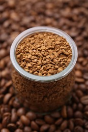 Photo of Glass jar with granulated instant coffee on beans, closeup