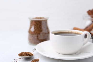 Photo of Cup of aromatic coffee and granulated instant coffee on white table, closeup. Space for text