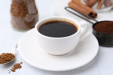 Photo of Cup of aromatic coffee and instant powder on white table, closeup