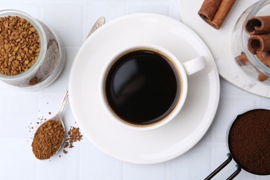 Photo of Cup of aromatic coffee and instant powder on white table, flat lay