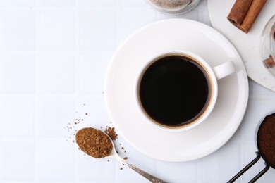 Photo of Cup of aromatic coffee and instant powder on white table, flat lay. Space for text