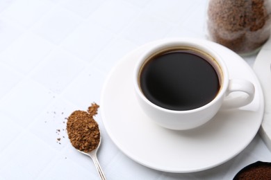 Photo of Cup of aromatic coffee and granulated instant coffee on white table, closeup. Space for text