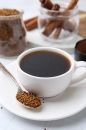 Photo of Cup of aromatic coffee and granulated instant coffee on white table, closeup