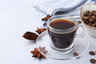 Photo of Cup of aromatic coffee, beans and star anise on white table, closeup. Space for text