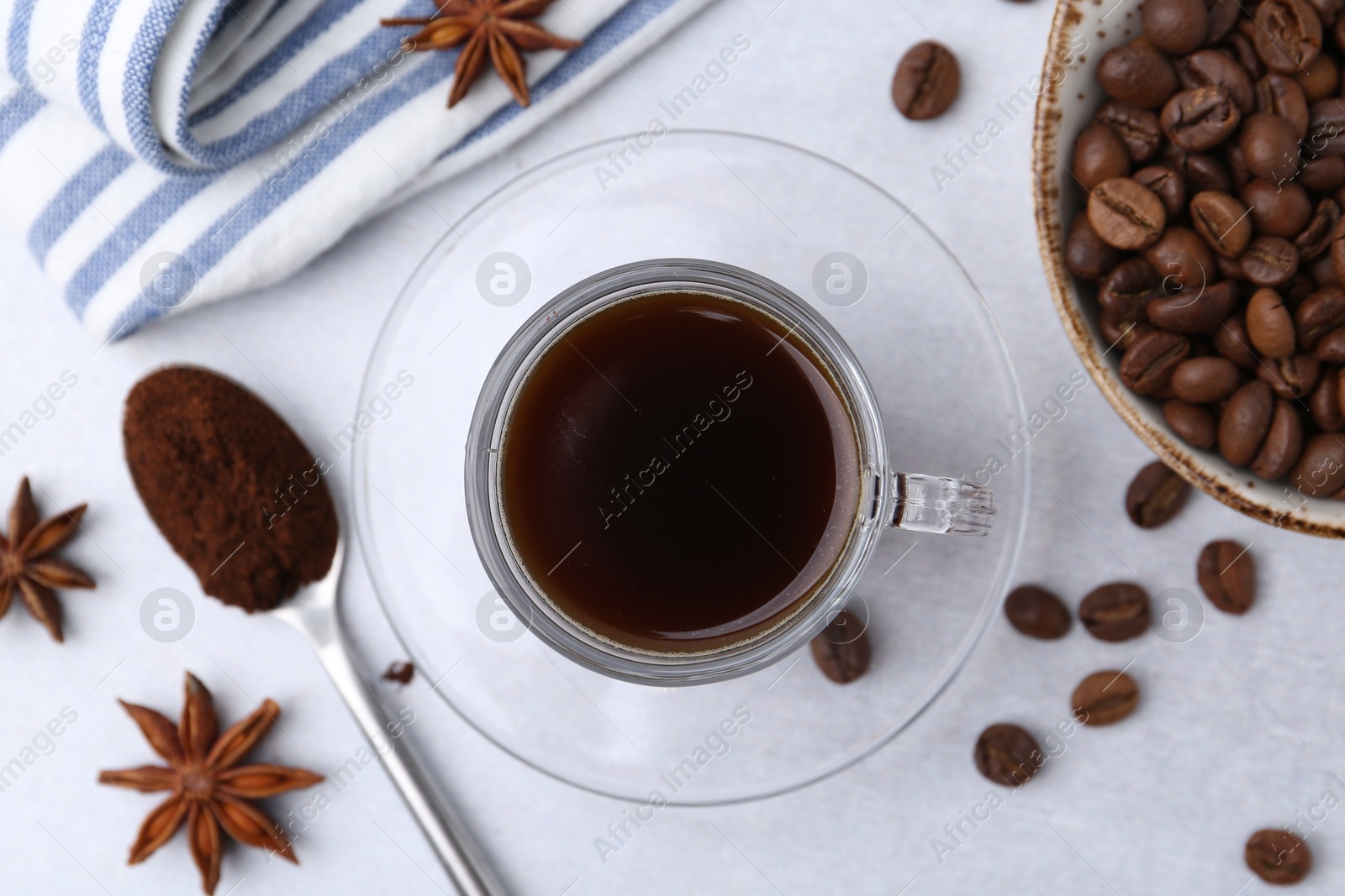 Cup of aromatic coffee, beans and star anise on white table, flat lay Photo of Cup of aromatic coffee, beans and star anise on white table, flat lay
