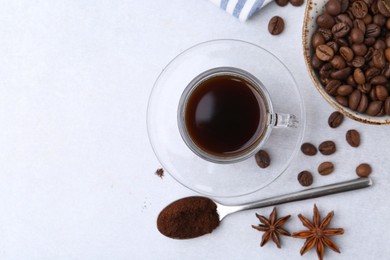 Photo of Cup of aromatic coffee, beans and star anise on white table, flat lay. Space for text