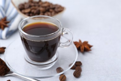 Photo of Cup of aromatic coffee, beans and star anise on white table, closeup. Space for text