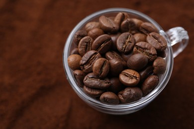 Photo of Cup of roasted coffee beans on powder, above view
