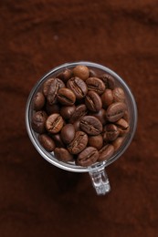 Photo of Cup of roasted coffee beans on powder, top view