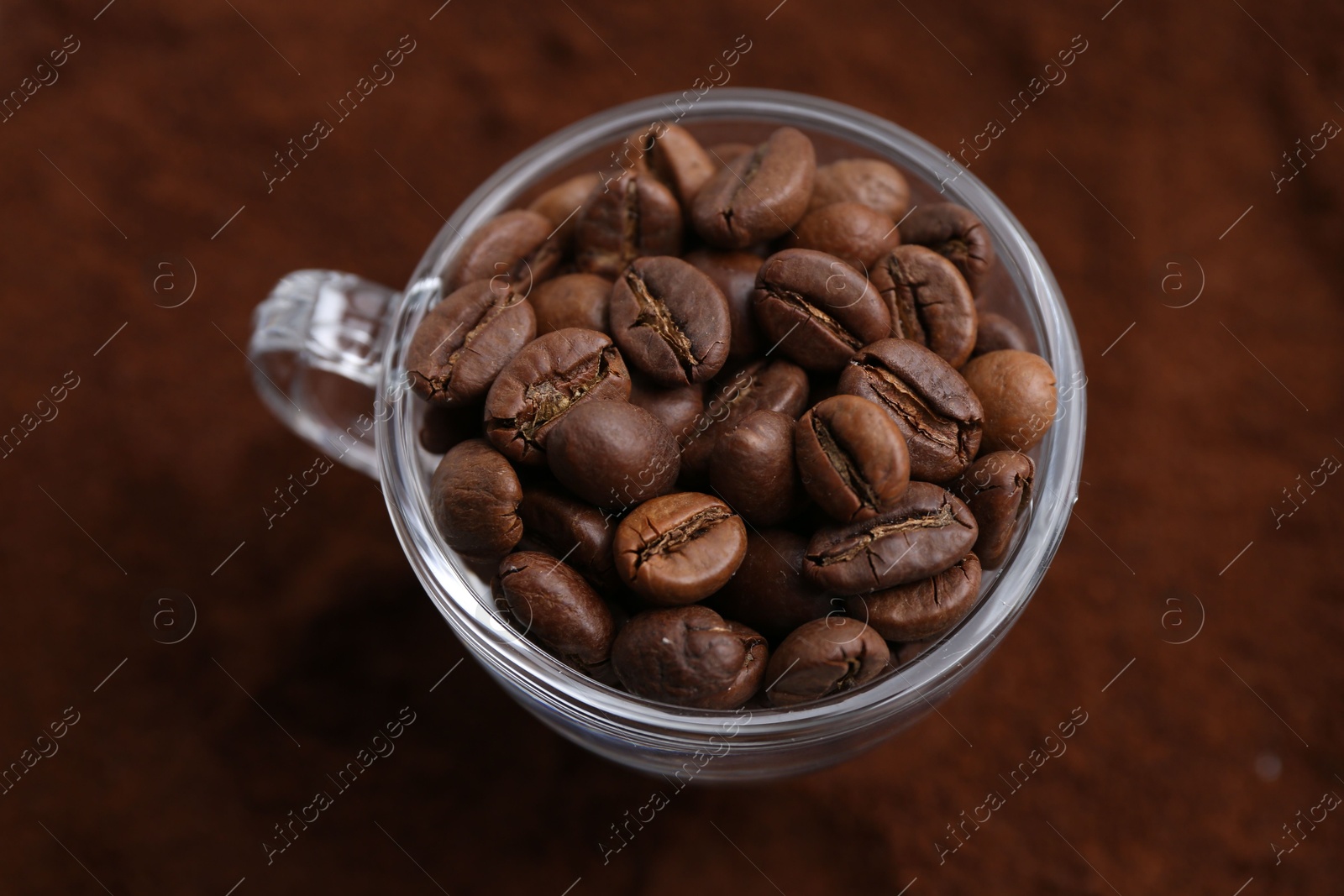 Photo of Cup of roasted coffee beans on powder, above view