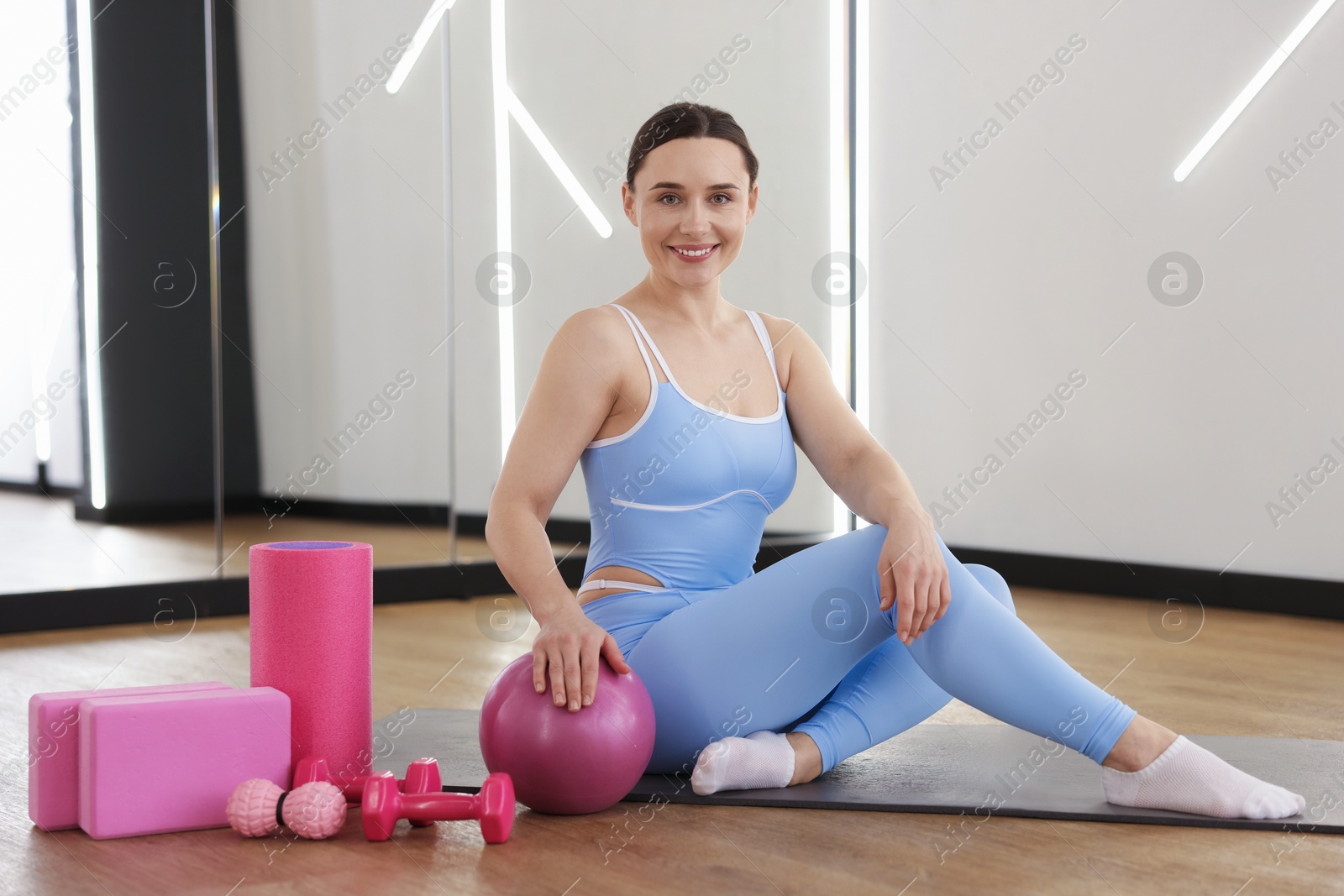 Woman with medicine ball and other sports equipment in fitness studio Photo of Woman with medicine ball and other sports equipment in fitness studio