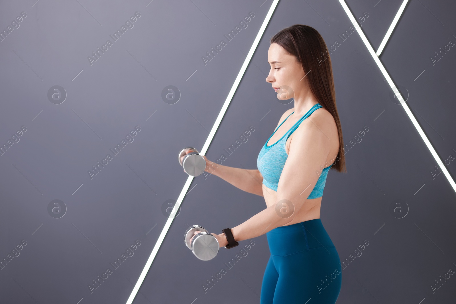 Woman exercising with dumbbells in fitness studio, space for text Photo of Woman exercising with dumbbells in fitness studio, space for text