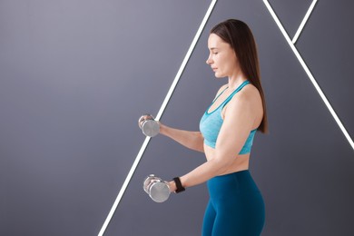 Photo of Woman exercising with dumbbells in fitness studio, space for text