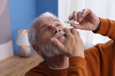 Photo of Senior man applying eye drops at home