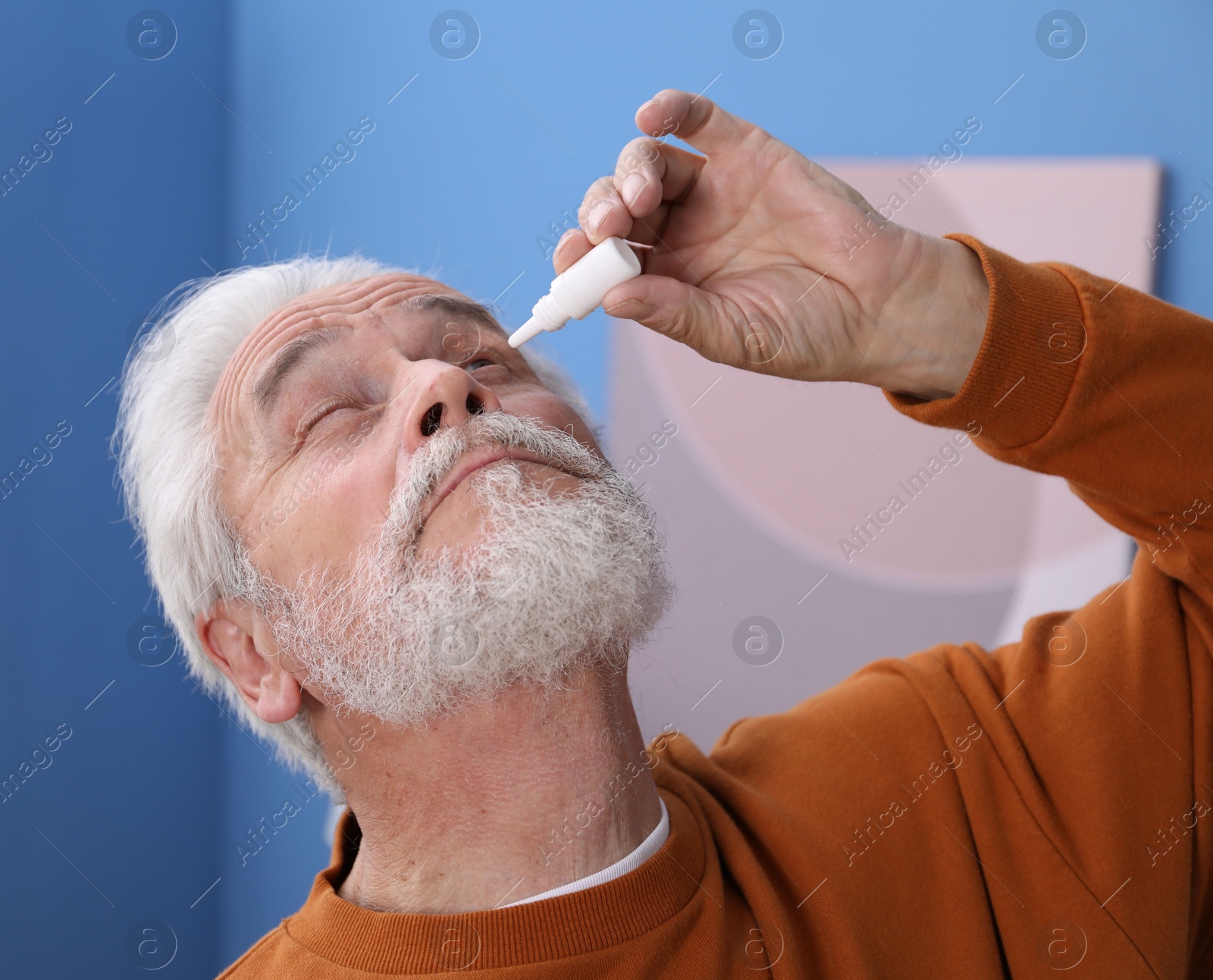 Senior man applying eye drops at home Photo of Senior man applying eye drops at home