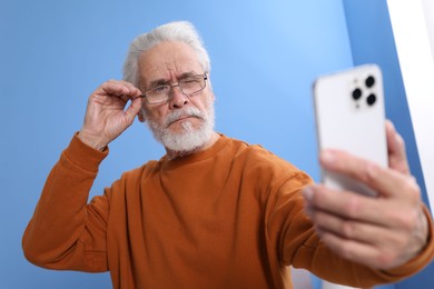 Photo of Senior man with vision problem using smartphone at home