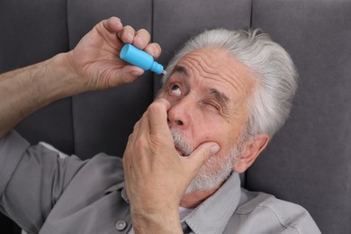 Photo of Senior man applying eye drops on bed at home