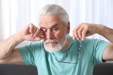 Photo of Senior man with glasses suffering from eyestrain at home