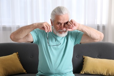 Photo of Senior man with glasses suffering from eyestrain at home