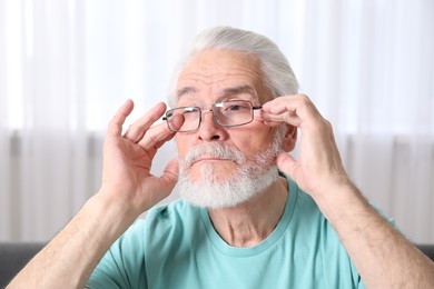 Photo of Senior man in glasses suffering from eyestrain at home