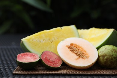 Photo of Ripe juicy tropical fruits on wicker table, closeup
