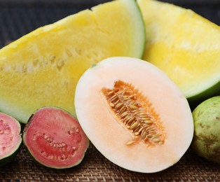 Photo of Ripe juicy tropical fruits on wicker table, closeup