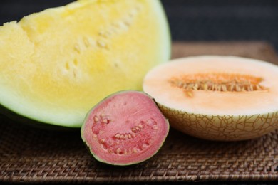 Photo of Ripe juicy tropical fruits on wicker table, closeup