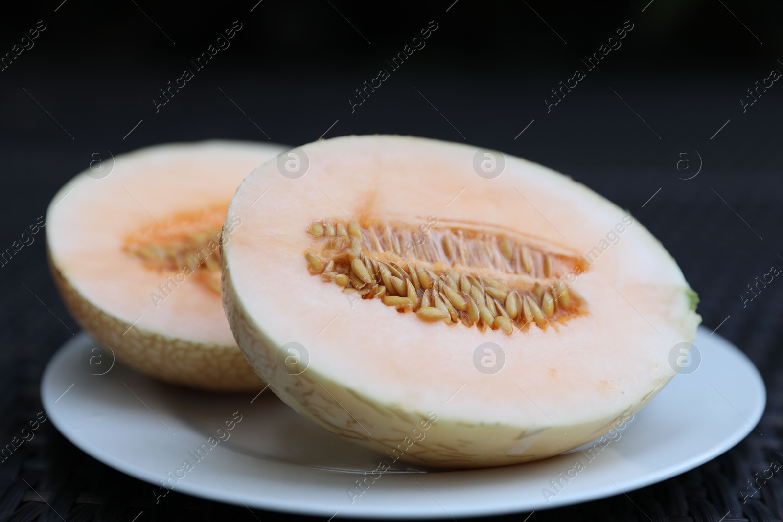 Halves of juicy melon on wicker table, closeup Photo of Halves of juicy melon on wicker table, closeup