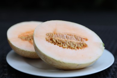 Photo of Halves of juicy melon on wicker table, closeup