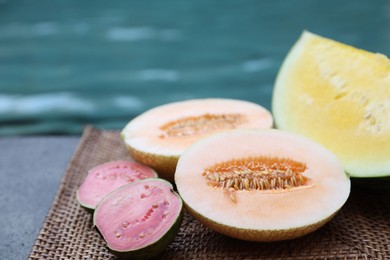 Photo of Ripe juicy tropical fruits on wicker tray near swimming pool, closeup
