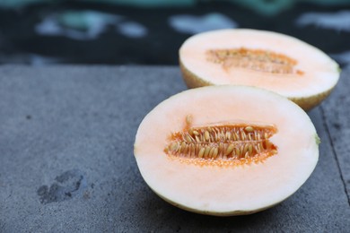 Photo of Halves of juicy melon on grey surface near swimming pool, closeup. Space for text
