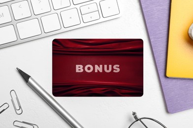 Image of Bonus card with stylish design, stationery and computer keyboard on white table, flat lay
