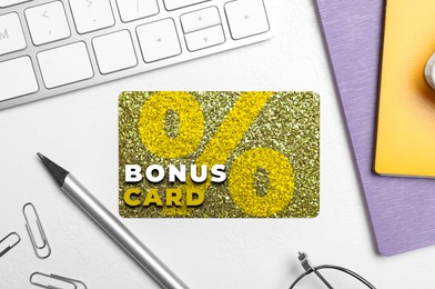 Image of Bonus card with stylish design, stationery and computer keyboard on white table, flat lay