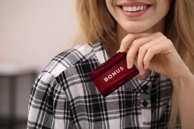 Image of Woman holding Bonus card with stylish design, closeup